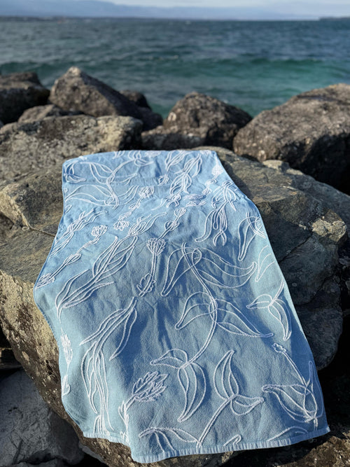 Light blue fabric with aquatic plant patterns on rocks by the water
