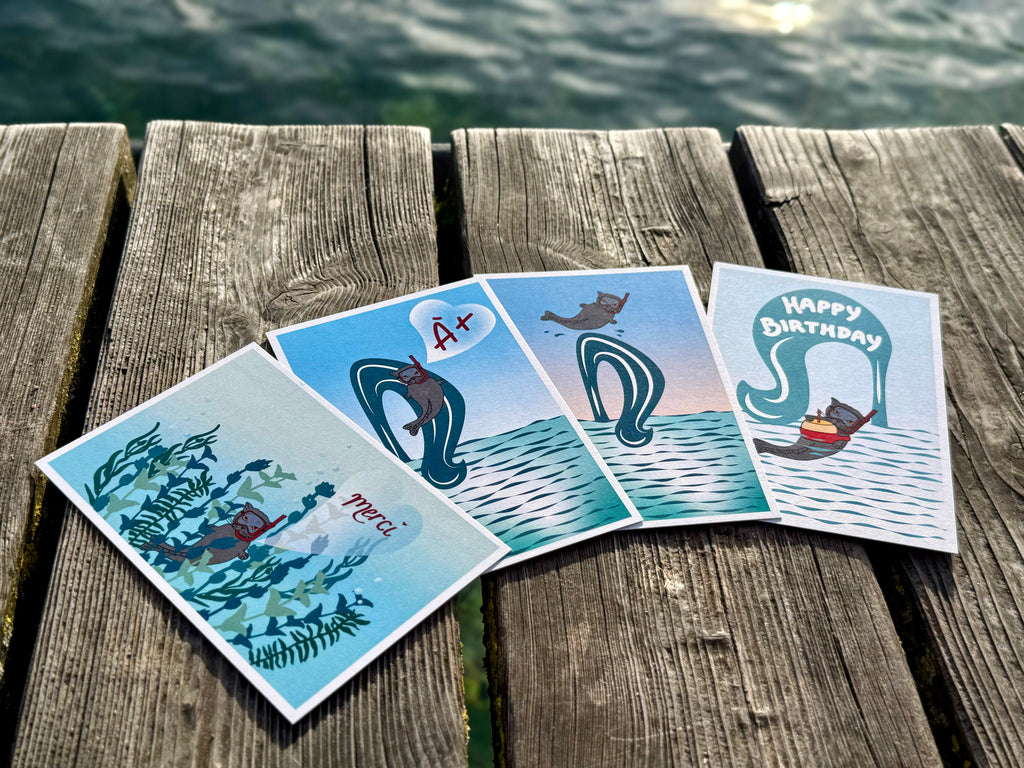 4 illustrated postcards of Catfish Darsea lie arranged on wooden planks over water